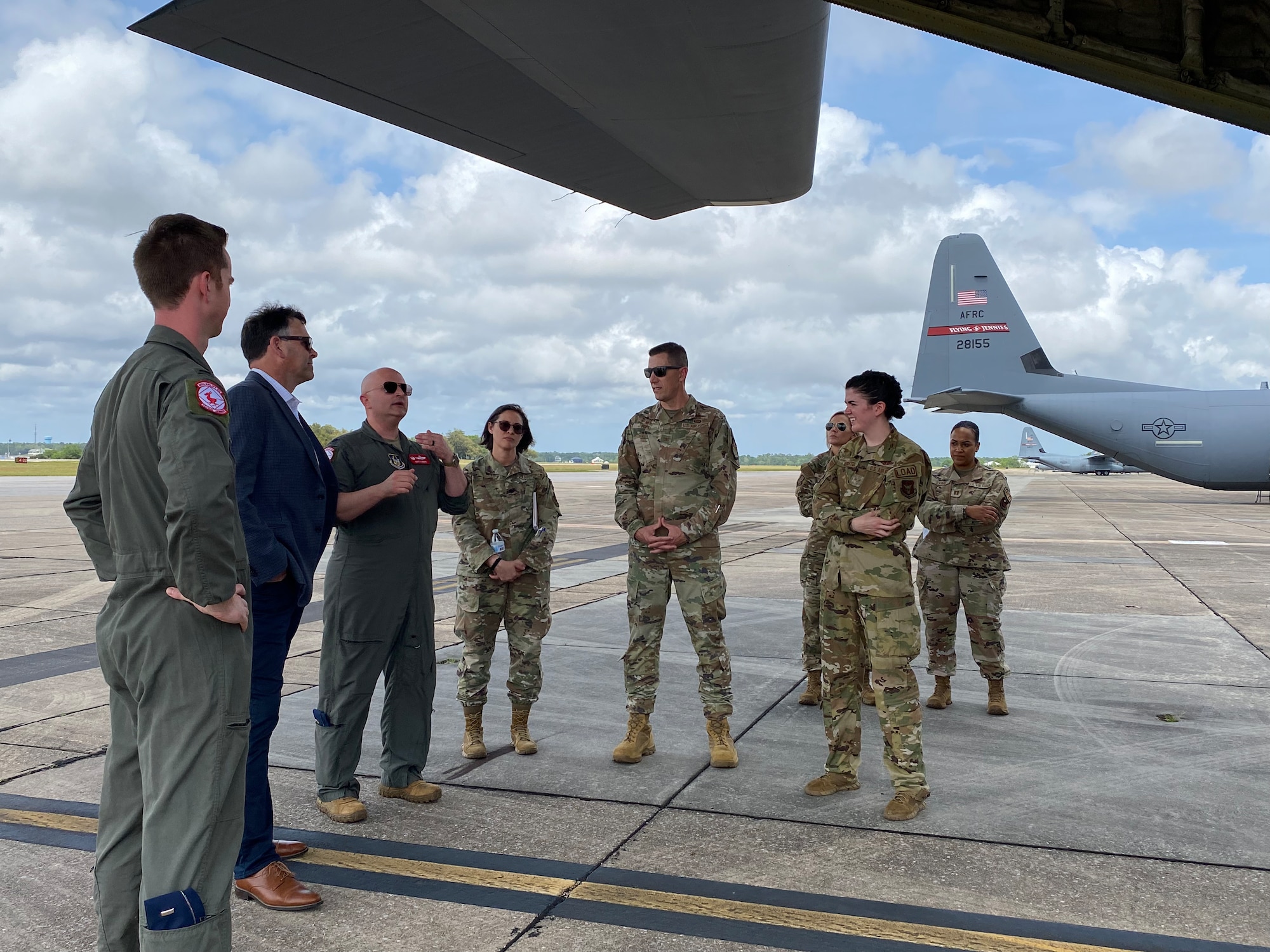 MS Secretary of State and military Airmen stand under the tail of a C-130J Super Hercules.