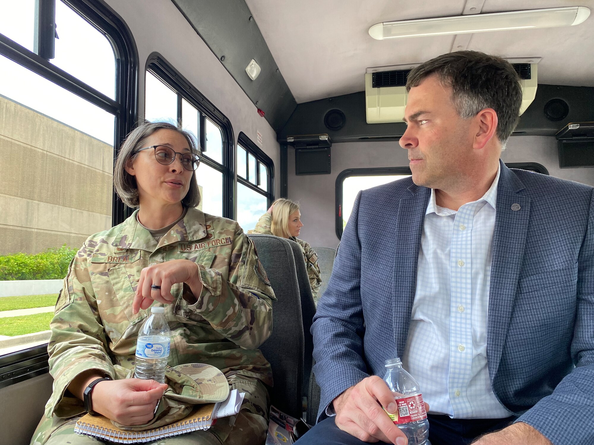 Military officer and MS Secretary of State sit on surrey bus and talk.