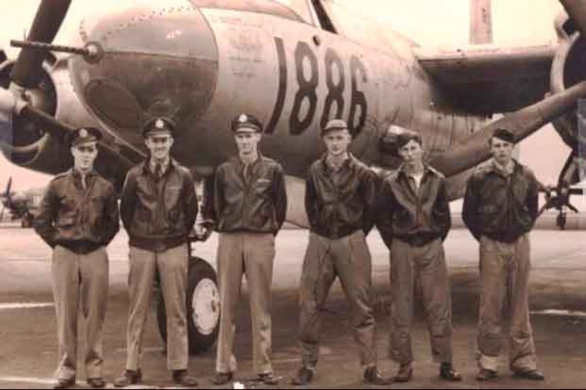 A group of airmen pose for a picture in front of an airplane.