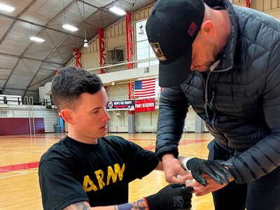 Sgt. Alex Robison gets taped up before wheelchair rugby training by 2023 Team Army Gold Medalist Sgt. Shawn Lee at Fort Belvoir.