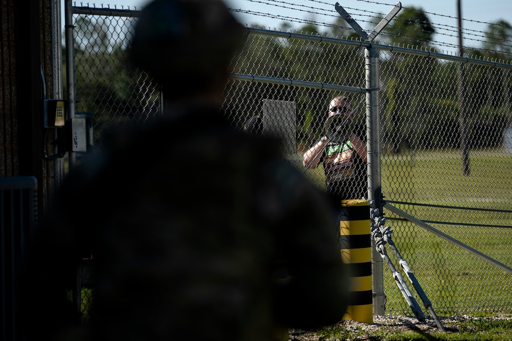 A U.S. Air Force Airman assigned to a base defense team during Exercise Ready Tiger 24-1 stands by for a protest training scenario at Avon Park Air Force Range, Florida, April 12, 2024. Security forces Airmen and augmentees worked together to de-escalate the protest and ensure security for personnel and assets at Forward Operating Site Avon. The Ready Tiger 24-1 exercise evaluators will assess the 23rd Wing's proficiency in employing decentralized command and control to fulfill air tasking orders across geographically dispersed areas amid communication challenges. (U.S. Air Force photo by Tech. Sgt. Devin Boyer)