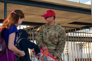 An Airman hands out candy to passing by school children