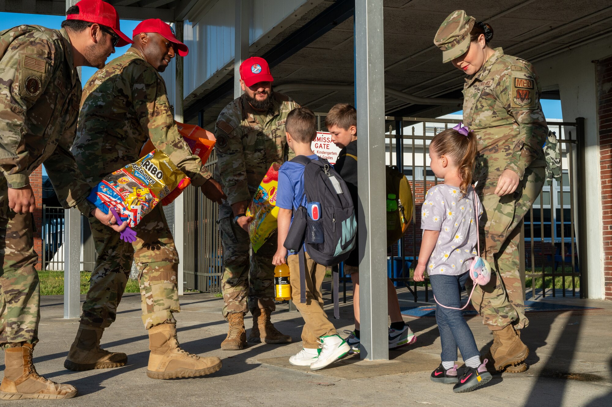 Military members hand candy to passing by school children