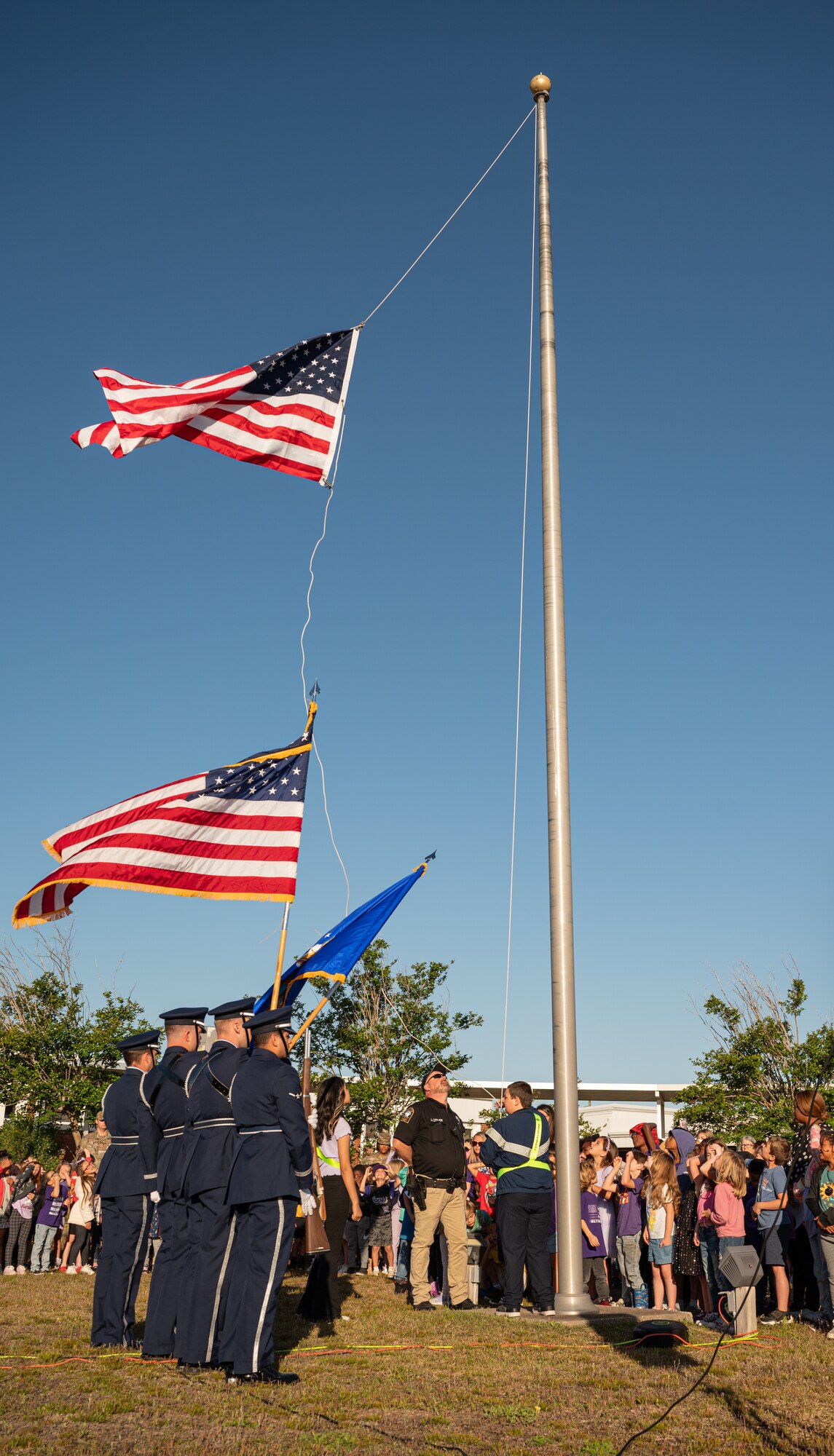 A crowd of people stand around the American Flag