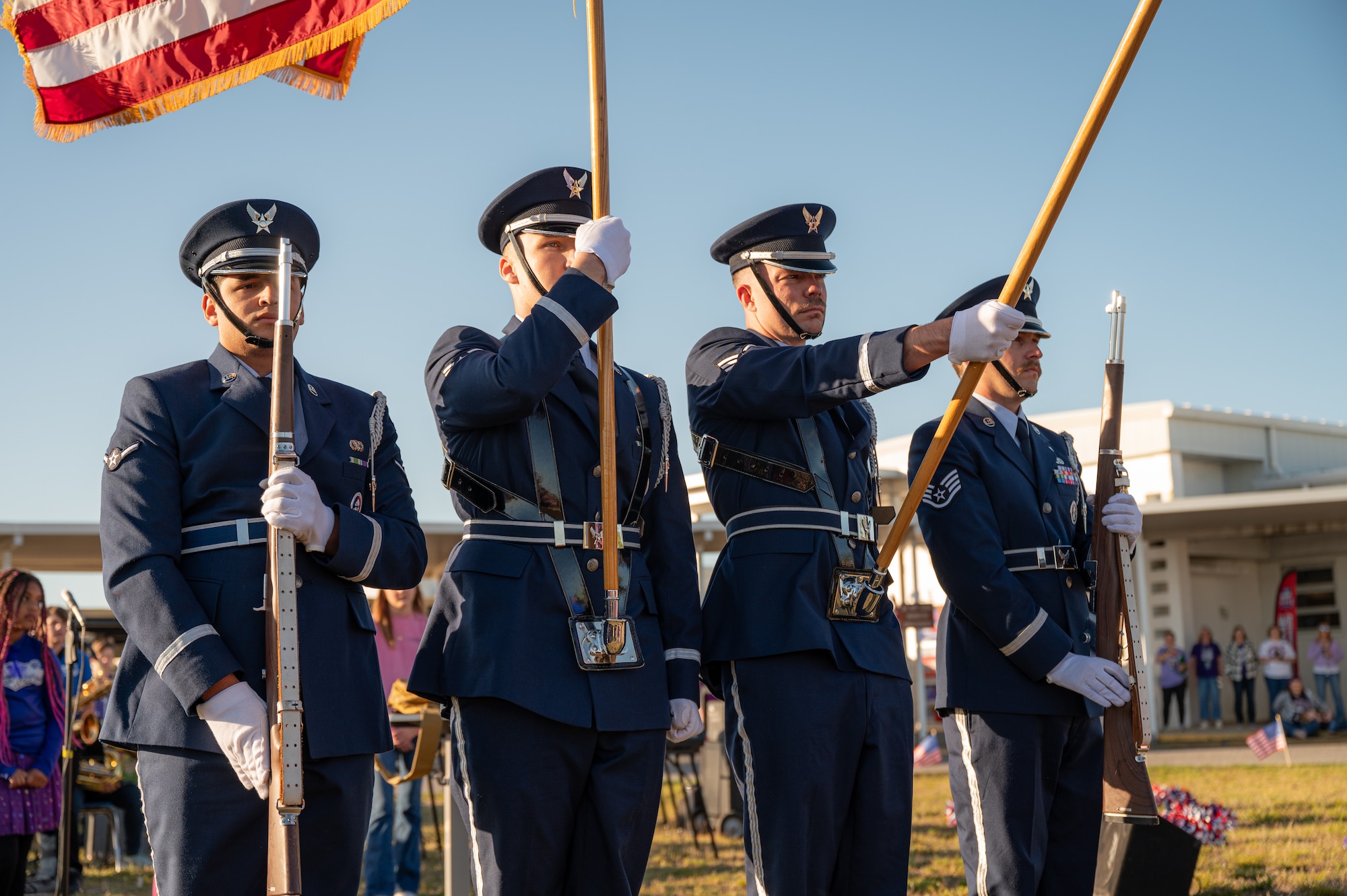 Airmen hold flags and rifles for a ceremony