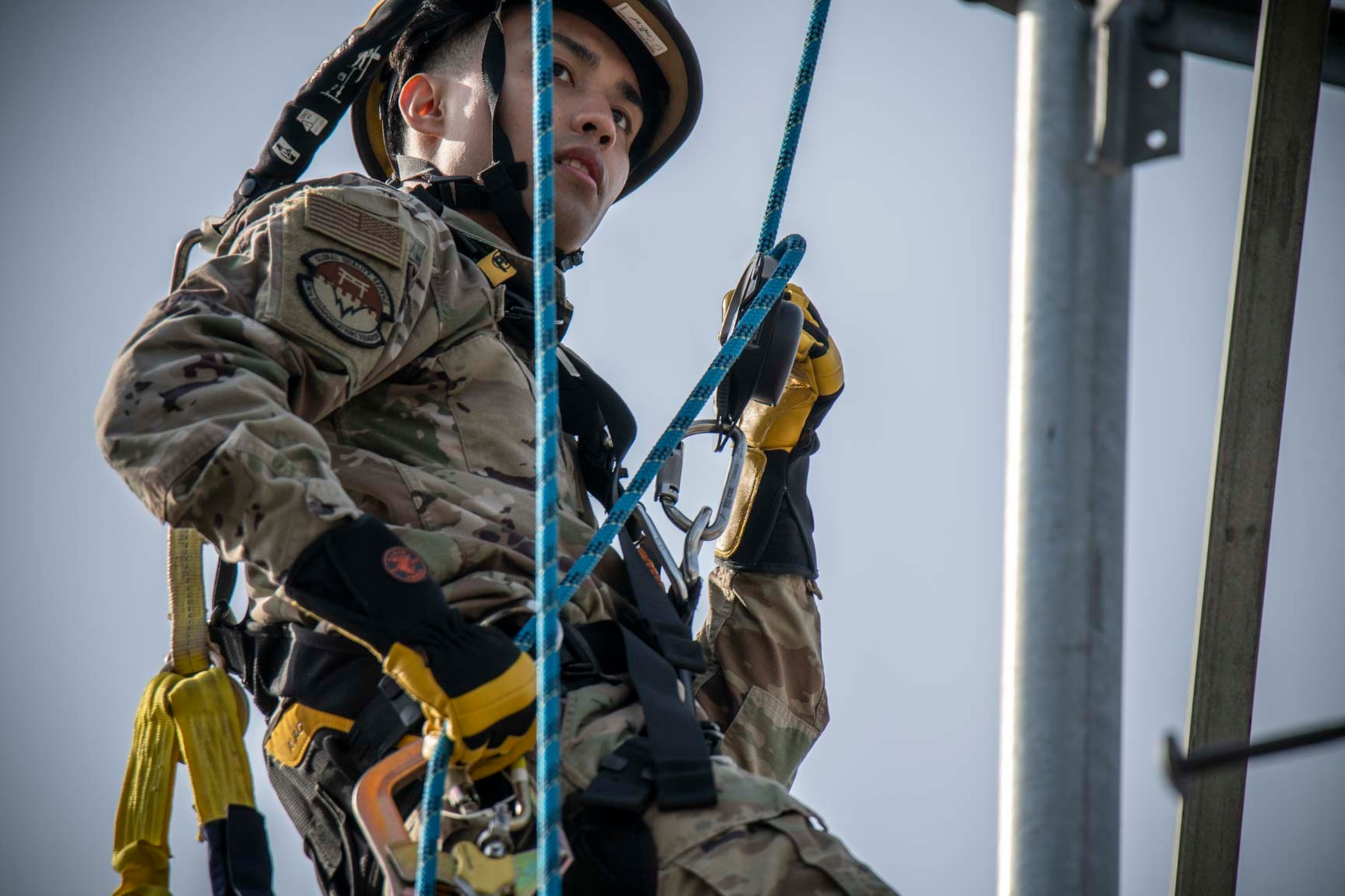 A military member repels down a tower.