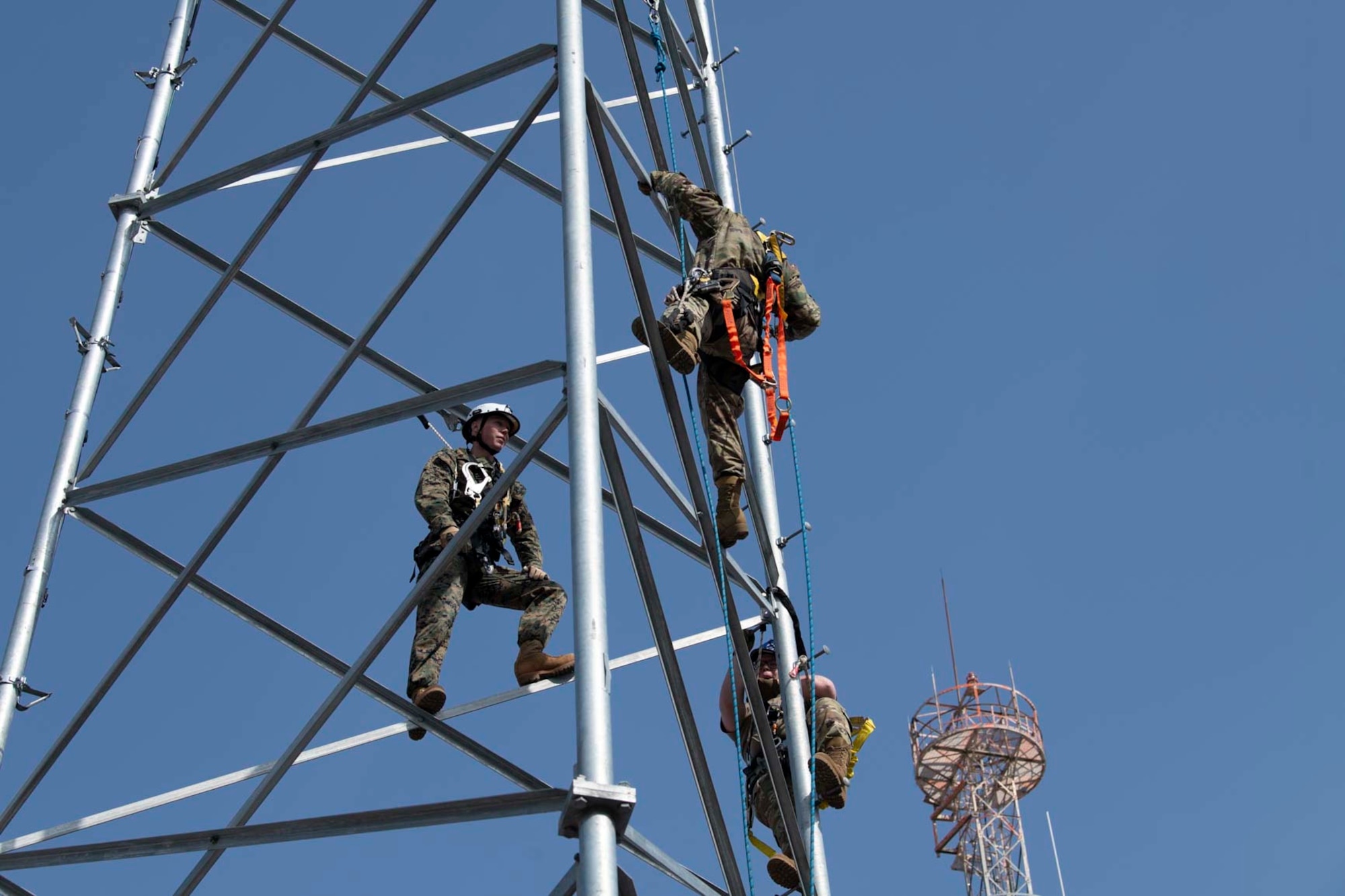 Three military members stand on top of a tower.