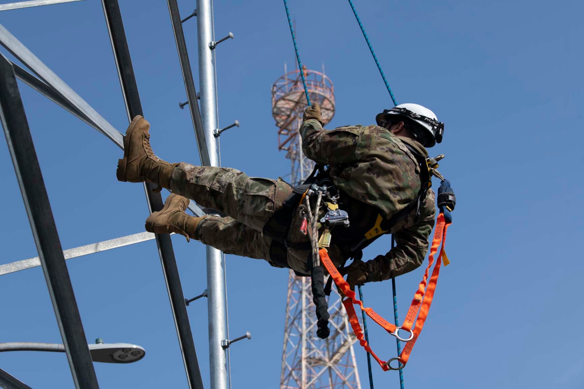 A military member rappels down a tower.