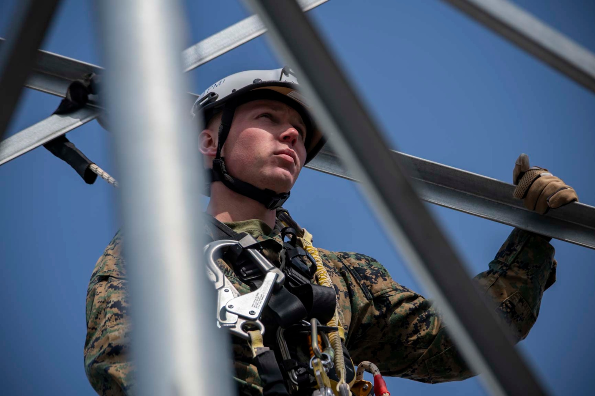 A military member holds on to a metal tower.