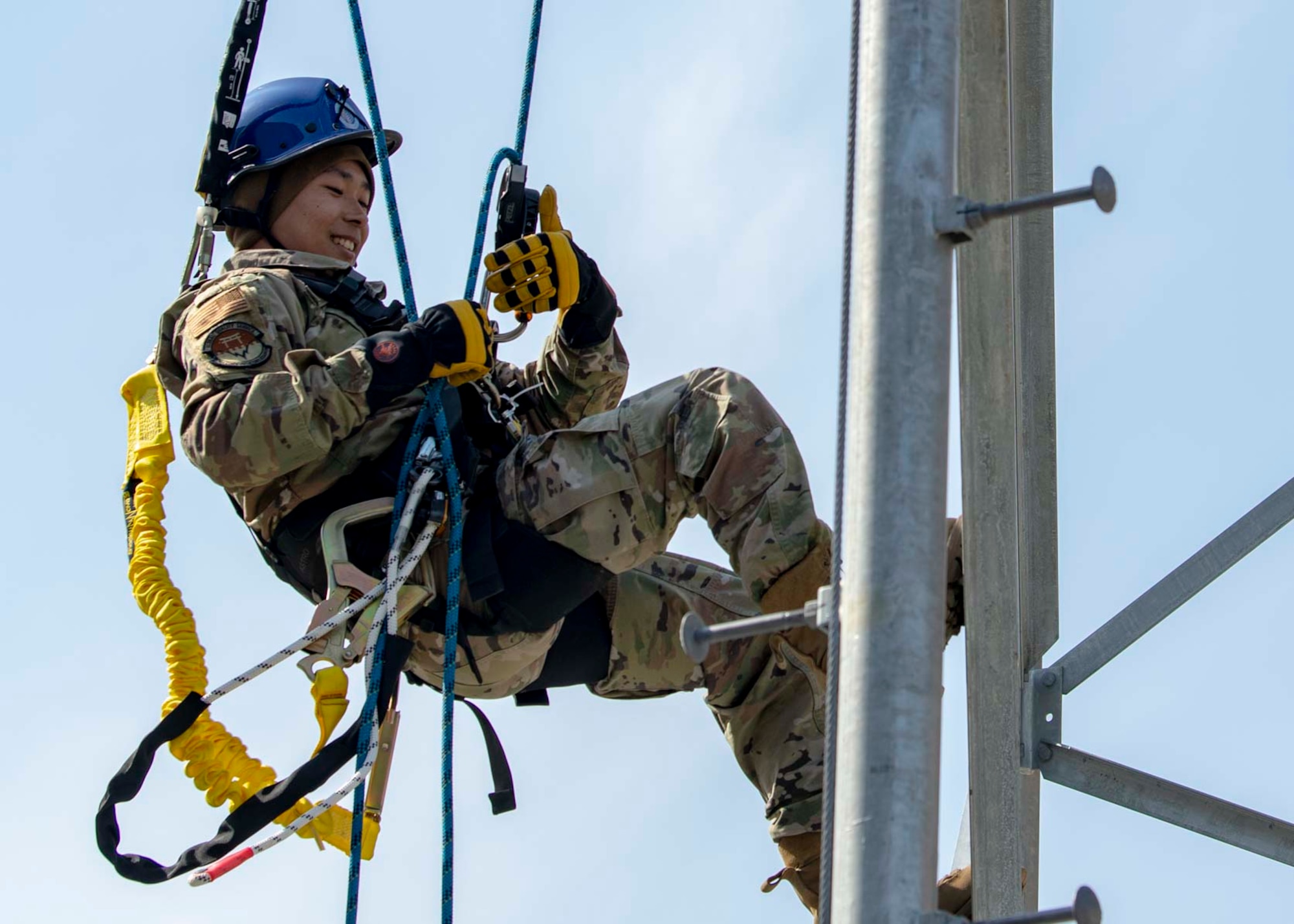 A military member climbs down the side of a tower.
