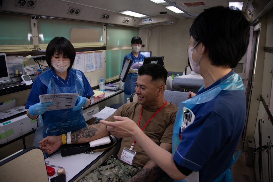 U.S. Navy Builder 2nd Class Craig Quichocho, a facilities locksmith with Headquarters and Headquarters Squadron, Marine Corps Air Station Iwakuni, is given instructions before giving blood at MCAS Iwakuni, Japan, April 11, 2024. The blood drive was the first bilateral blood drive with the Japanese and American Red Cross on MCAS Iwakuni in over four and a half years due to COVID-19 restrictions. (U.S. Marine Corps photo by Lance Cpl. Rylan Adcock)