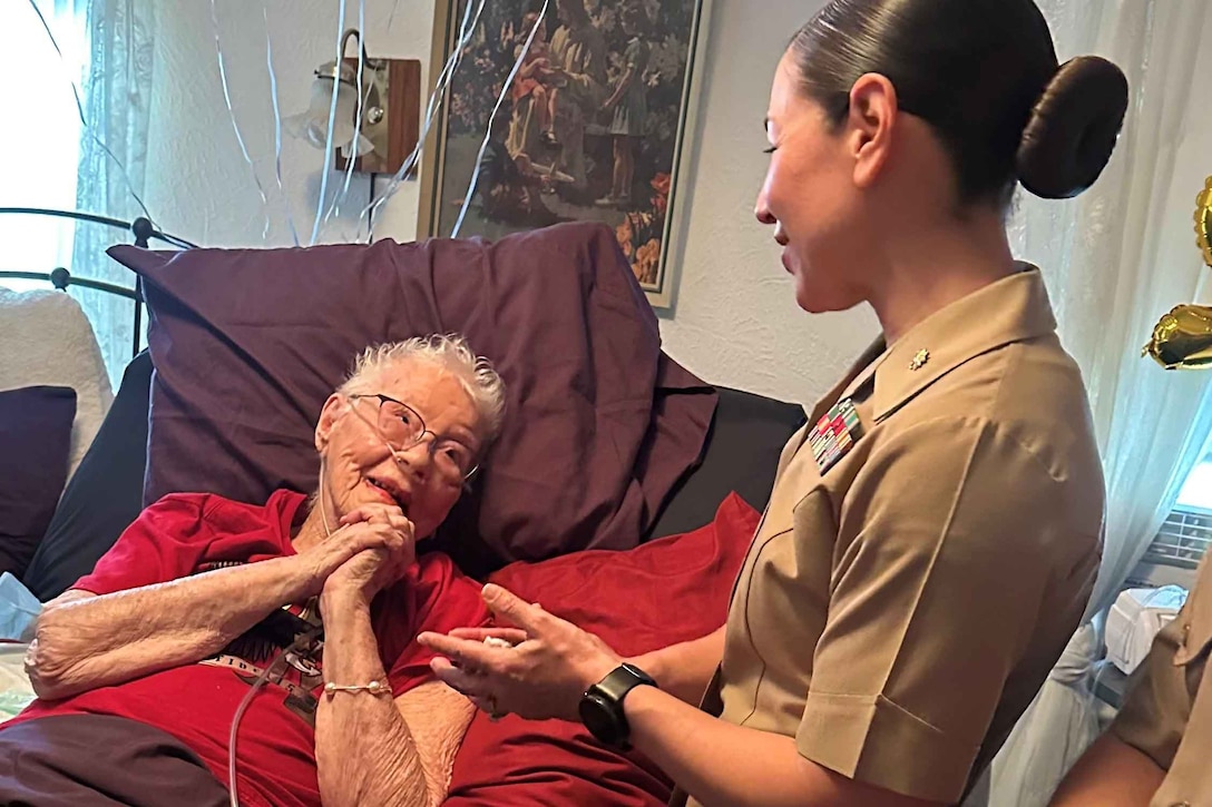 A Marine speaks with a civilian lying in a bed.