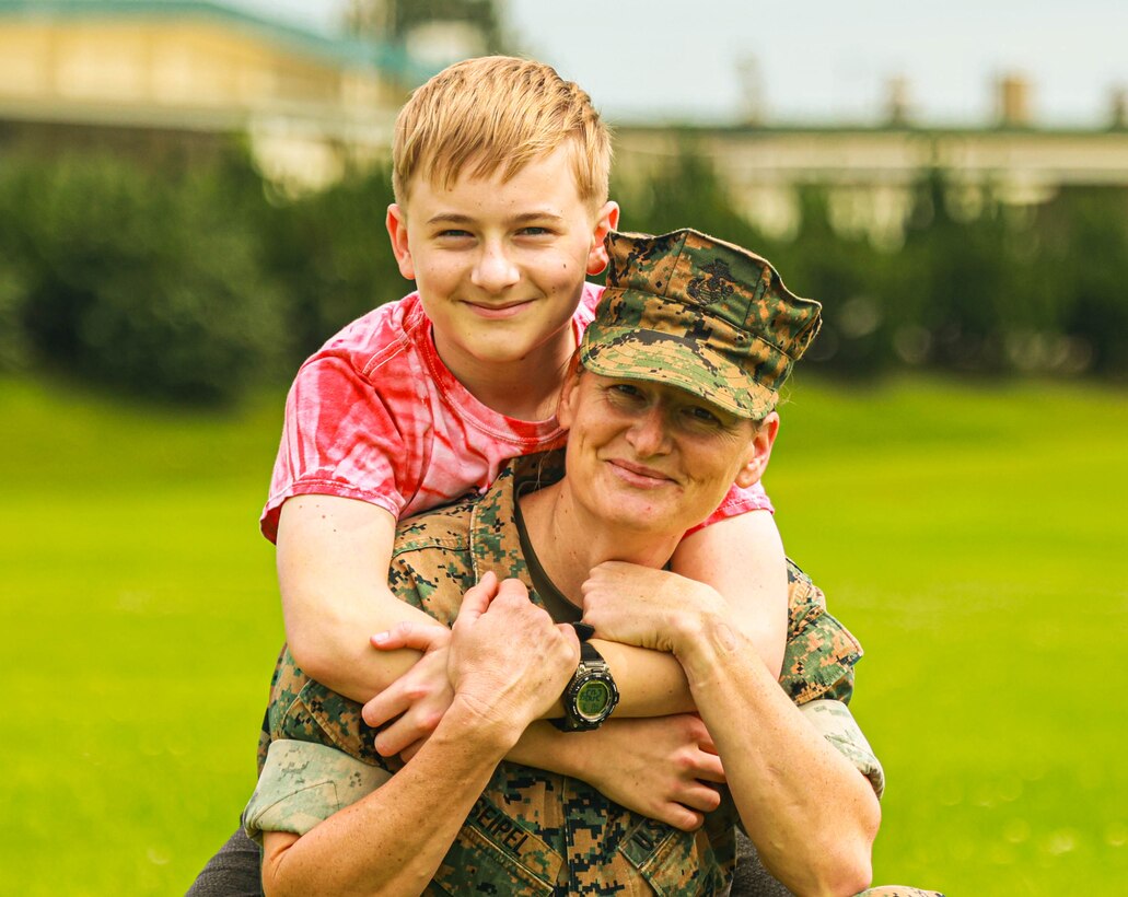 Harley Seipel embraces his mother, Col. Petra Seipel, the senior officer in charge of supply and logistics at the 3rd Marine Expeditionary Brigade, on Camp Courtney, Okinawa, Japan, April 9, 2024. The Month of the Military Child, celebrated annually in April, recognizes military children for the daily sacrifices and challenges they overcome. (U.S. Marine Corps photo by 1st Lt. Samuel H. Barge)