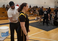 Team Army Coach Ross Alewine puts powder on the shoulder blades of U.S. Army veteran Maj. Victoria Camire during the powerlifting event at the 2024 Army Trials, Fort Liberty, North Carolina