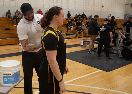 Team Army Coach Ross Alewine puts powder on the shoulder blades of U.S. Army veteran Maj. Victoria Camire during the powerlifting event at the 2024 Army Trials, Fort Liberty, North Carolina