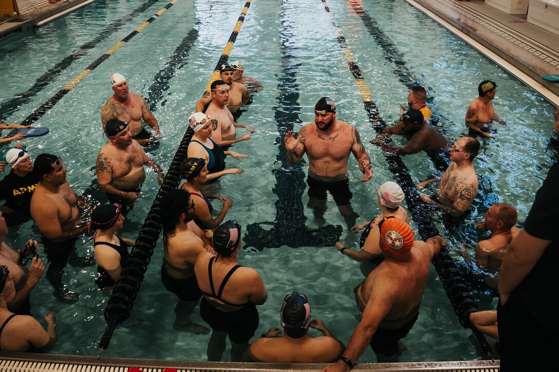Team Army athletes receive event instructions from coach Ross Alewine, center, during the swimming event at the 2024 Army Trials, Fort Liberty, North Carolina