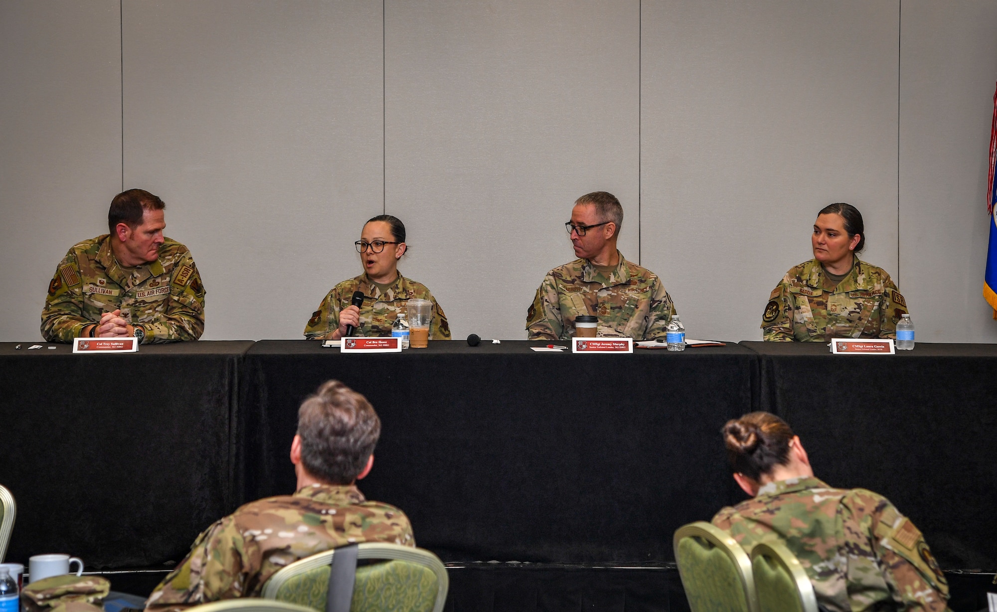 Four individuals sit at a table and talk to group with a mic.