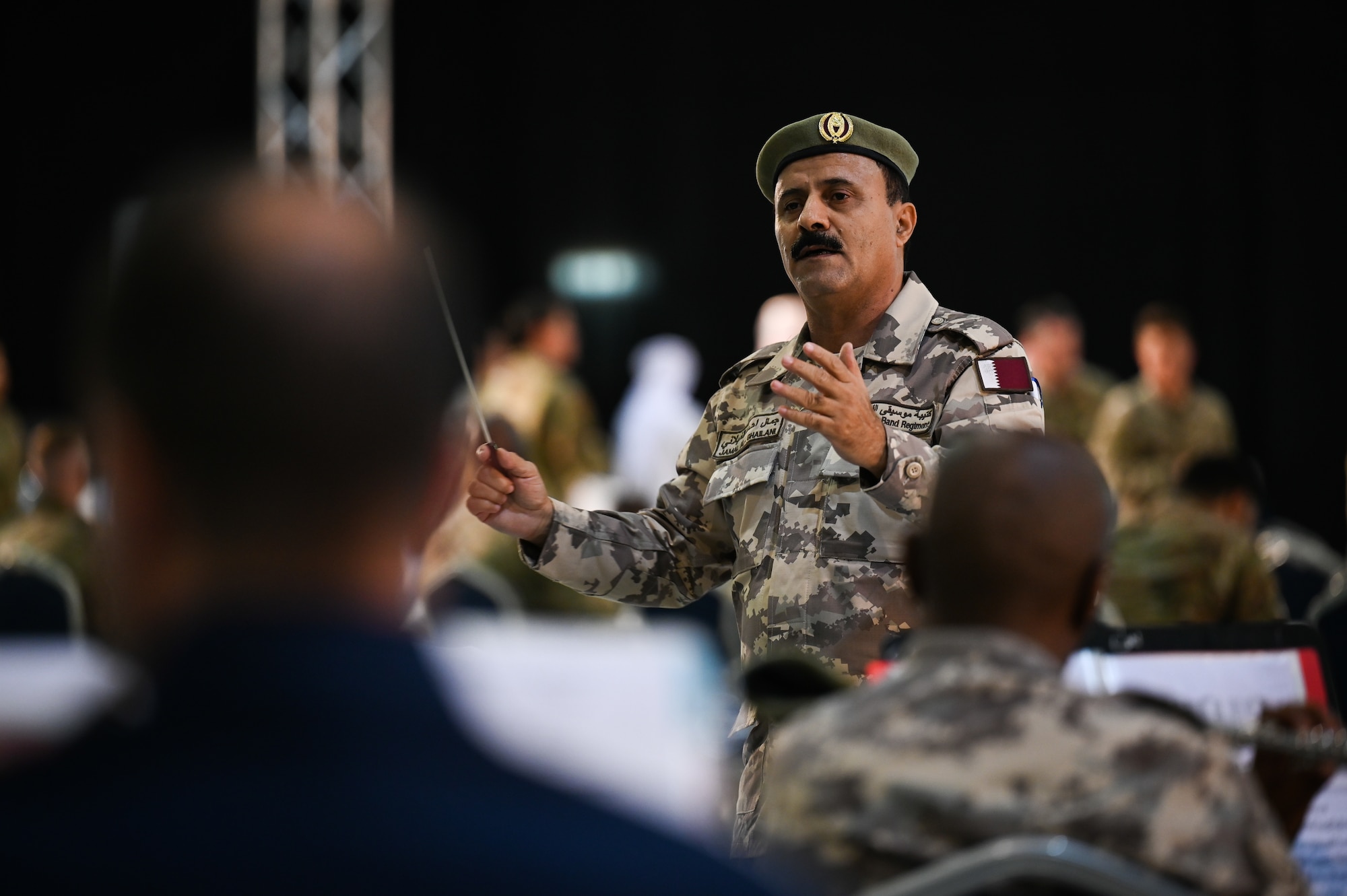 A Qatari Emiri Air Force band member conducts a U.S. Air Force and Qatari joint service band during Lt. Gen. Derek France's change of command ceremony at Al Udeid Air Base, Qatar, April 18, 2024. Hundreds of Airmen, joint and coalition partners, and senior regional military officials attended the ceremony, highlighting the U.S.’s focus on building and maintaining critical partnerships through a collective vision for peace and security throughout the region. (U.S. Air Force photo)