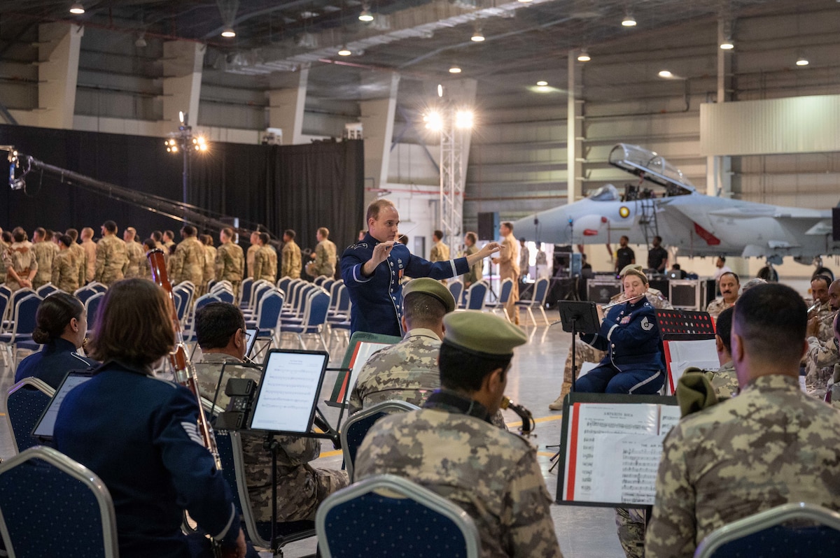 A United States Air Force Central Command Airman conducts a U.S. Air Force and Qatari joint service band during Lt. Gen. Derek France's change of command ceremony at Al Udeid Air Base, Qatar, April 18, 2024. AFCENT is headquartered at Shaw Air Force Base, South Carolina, and has a forward headquarters at Al Udeid Air Base. AFCENT is a high performing, innovative team, executing an integrated campaign alongside regional and Coalition nations to deter and, if necessary, defeat regional aggressors and global competitors. (U.S. Air Force photo)