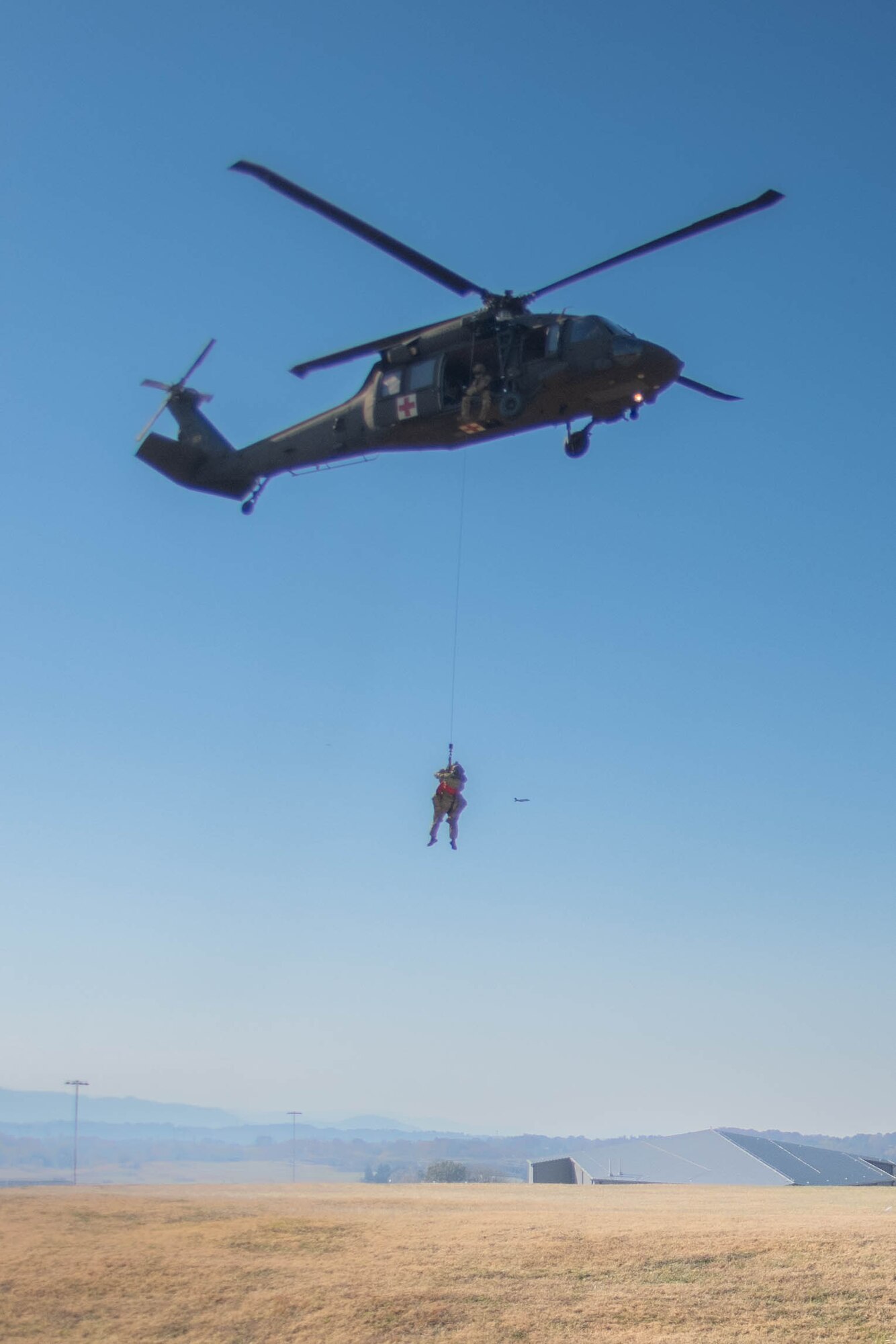 An Army Guardsman is lifted into a hovering helicopter