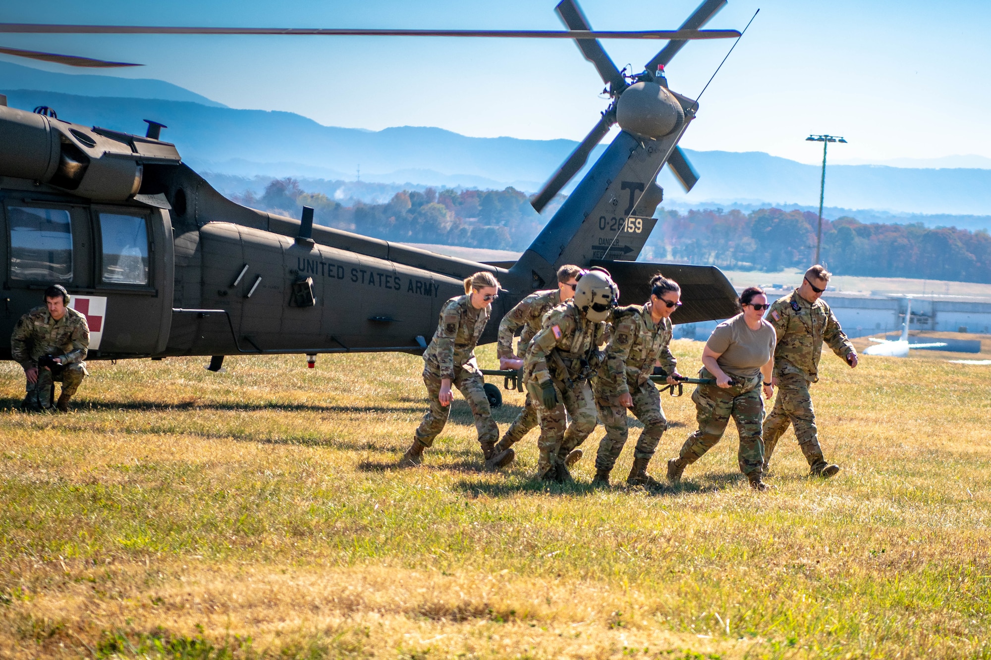 Airmen transport an injured person from a helicopter on a stretcher