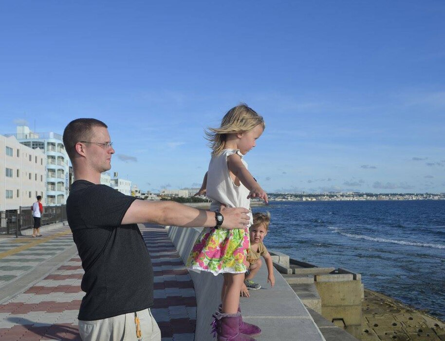 a father and daughter stand be a sea wall in Japan