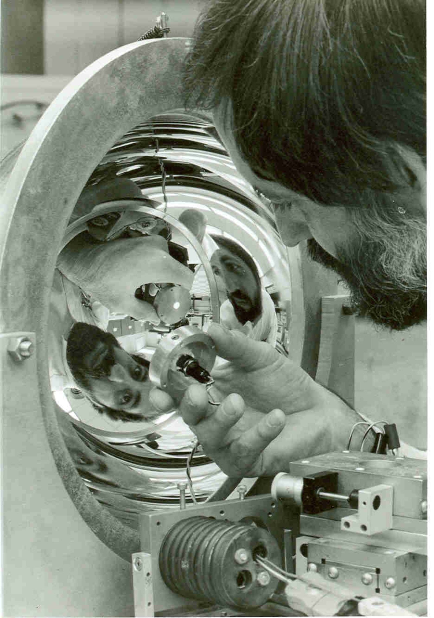 Arnold Engineering Development Center research engineer Bob Wood uses a light source to study a hemiellipsoidal mirror. The apparatus was to measure infrared reflectance of satellite materials and other hardware exposed to the cold temperatures of space. This image was featured on the frontpage of the February 1982 issue of High Mach. (U.S. Air Force photo)