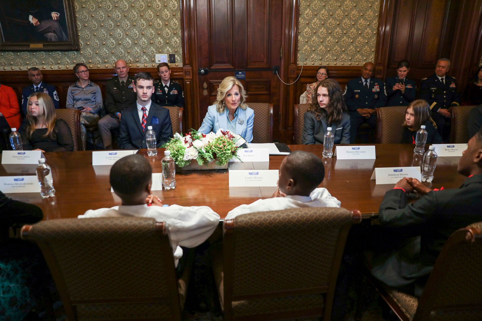 A woman in civilian attire sits at a table with children.