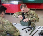 U.S. Army Sgt. Zach Joseph of HHC, 3-172nd Infantry (left), Spc. Zachary Keefer of A Co., 572nd BEB, 86th IBCT (MTN), Vermont National Guard, puts together a sincgars radio during the Best Warrior Competition.