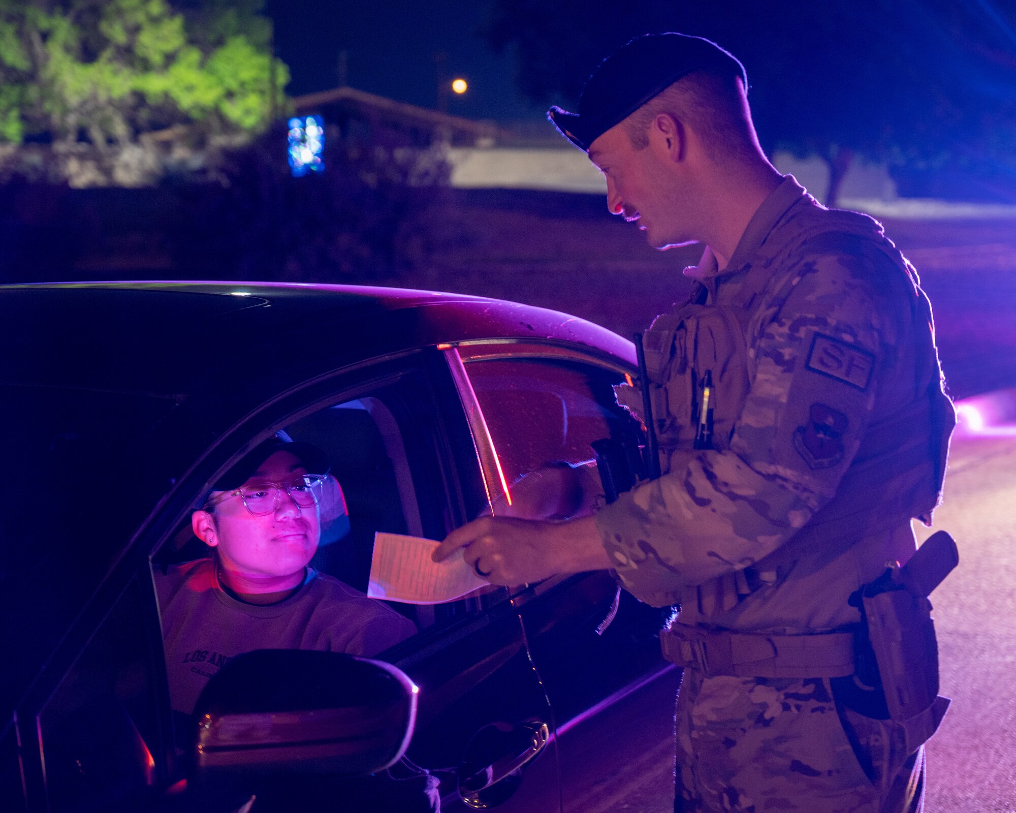 U.S. Air Force Staff Sgt. Siree Contreras, left, 47th Security Forces Squadron (SFS) noncommissioned officer in charge of police services, is given a ticket for distracted driving in a photoshoot with Staff Sgt. Ronnie Moore, right, 47th SFS flight sergeant, for Distracted Driving Awareness Month at Laughlin Air Force Base, Texas, April 4, 2024. April is Distracted Driving Awareness Month and the 47th SFS is looking to spread awareness of the causes and consequences of distracted driving. (U.S. Air Force photo by Staff Sgt. Nicholas Larsen)