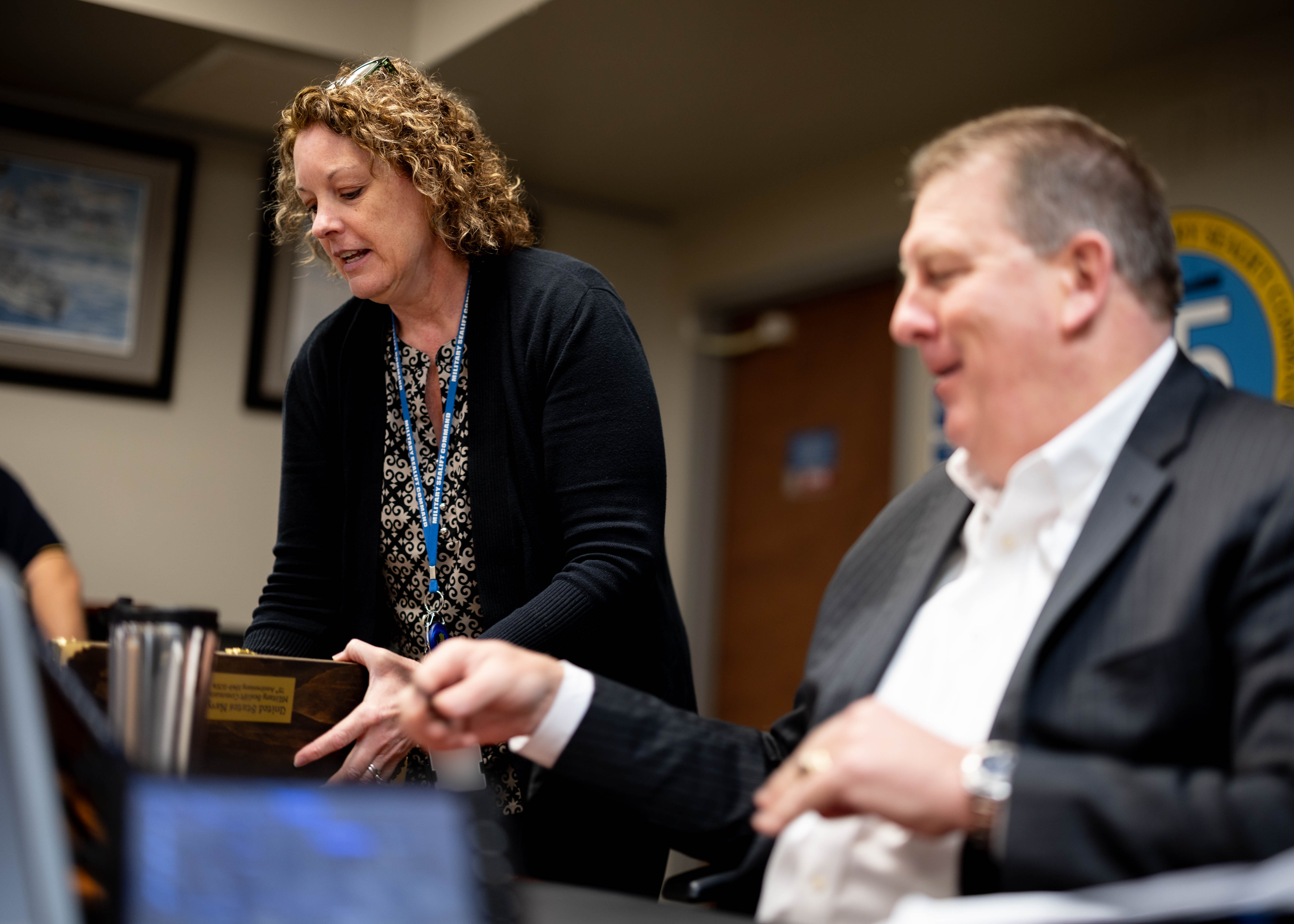 Johanna Crawford, supervisory associate council, Military Sealift Command (MSC), left, presents Steven C. Cade, Executive Director, MSC, right, with a 75th anniversary scroll to kick off the organization-wide signing of the document April 10, 2024. The scroll was designed to commemorate MSC's 75 years of maritime excellence.
