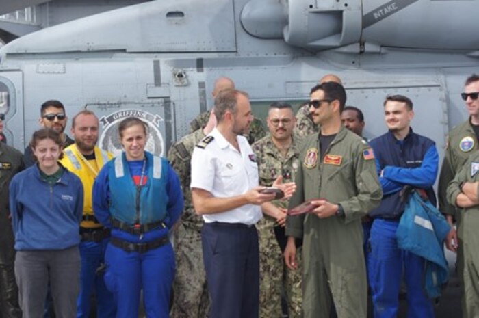 A Sailor from France’s Marine Nationale and a Sailor assigned to the “Griffins” of Helicopter Maritime Strike Squadron (HSM 79) exchange gifts during Strategic Interoperability Framework (SIF) testing, aboard French Navy amphibious assault ship LHD Dixmude (L9015), Apr. 16, 2024. SIF is a living, scalable plan aimed at ensuring high-end warfighting interoperability exists between the U.S. Navy and the Marine Nationale.