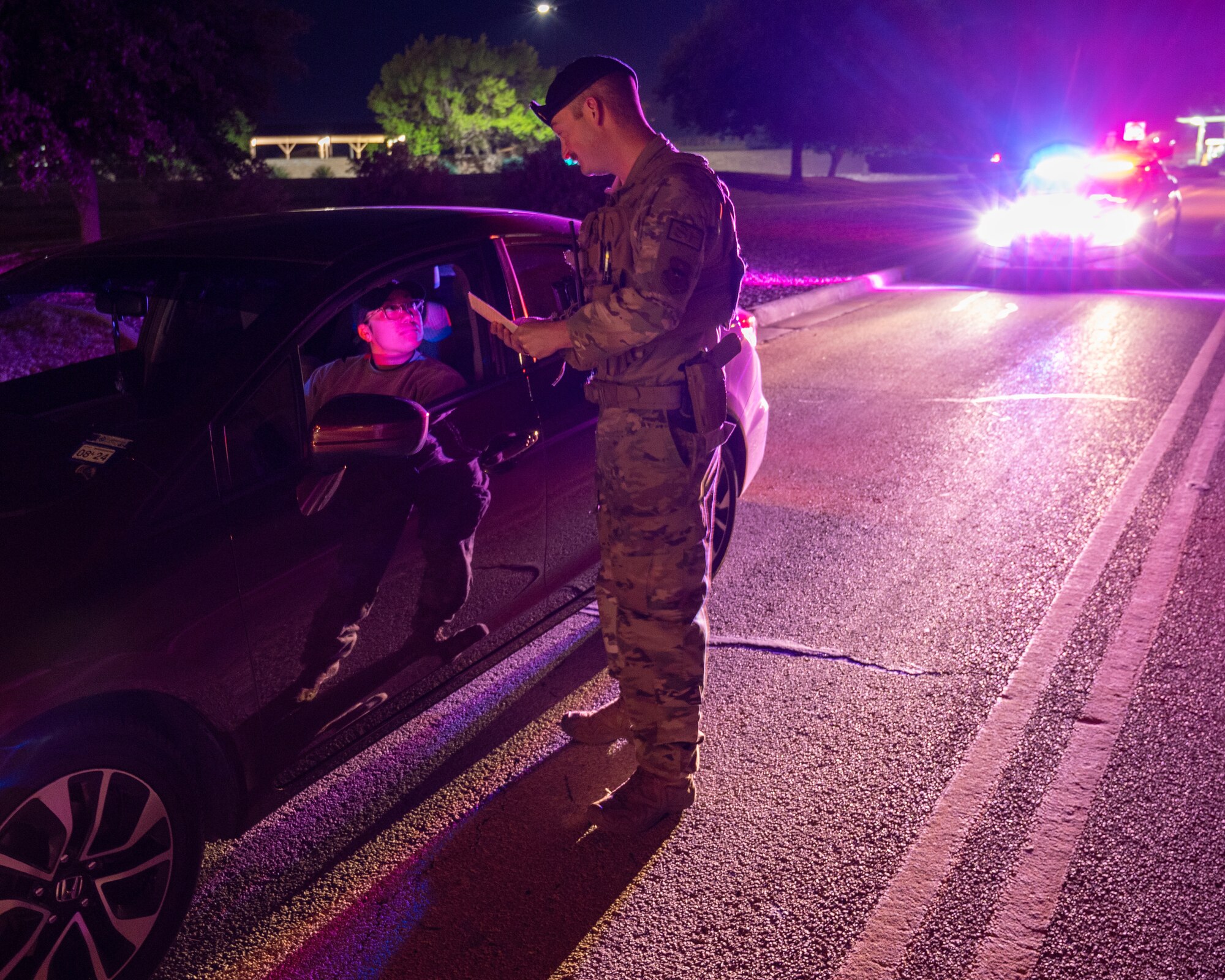 U.S. Air Force Staff Sgt. Siree Contreras, left, 47th Security Forces Squadron (SFS) noncommissioned officer in charge of police services, is given a ticket for distracted driving in a photoshoot with Staff Sgt. Ronnie Moore, right, 47th SFS flight sergeant, for Distracted Driving Awareness Month at Laughlin Air Force Base, Texas, April 4, 2024.  Distracted Driving on Laughlin has an escalating punishment, starting with a 15 day suspension of driving and leading up to a 6 month suspension. (U.S. Air Force photo by Staff Sgt. Nicholas Larsen)