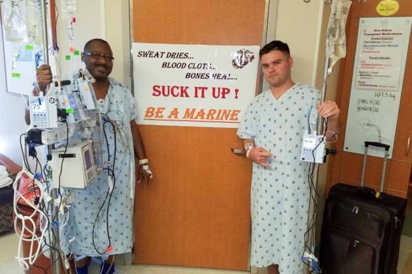 Two people wearing surgical gowns pose for a photo together.
