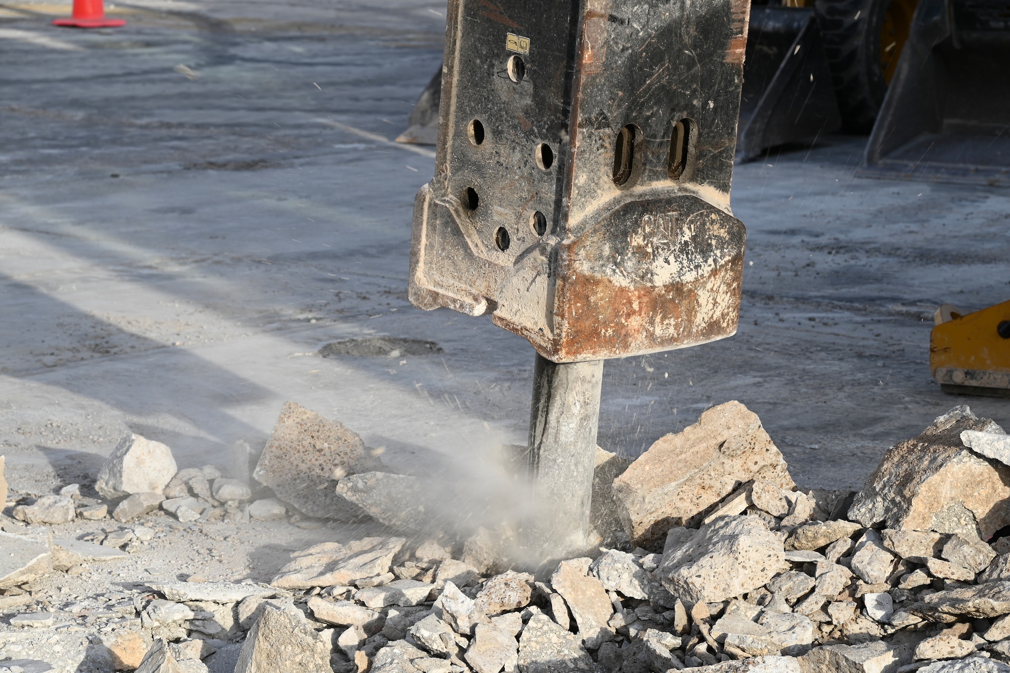 A excavator jack-hammer pierces through crushed stones and concrete.