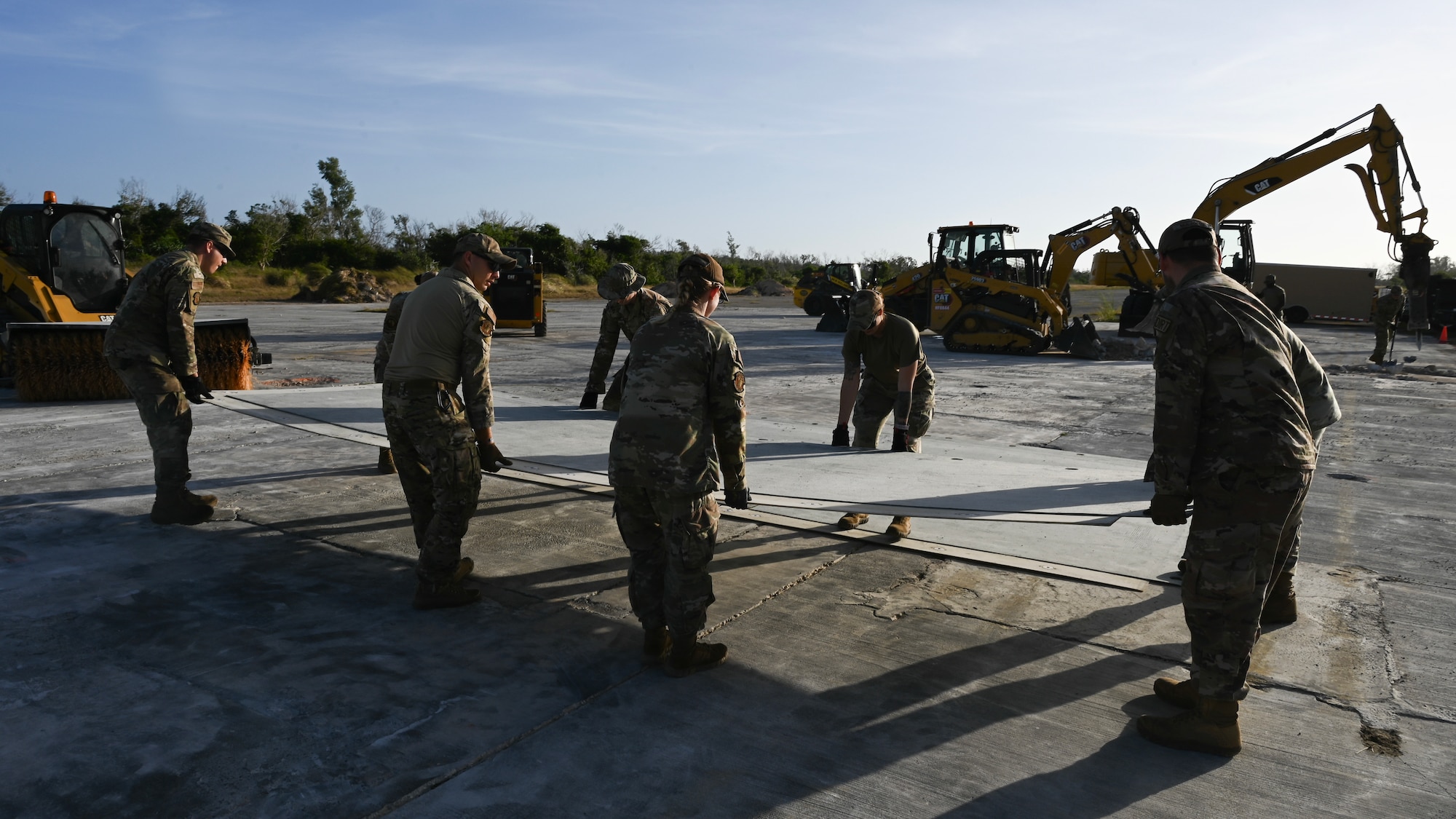 A team of Airmen lifts and transports a fiber reinforced polymer matting.