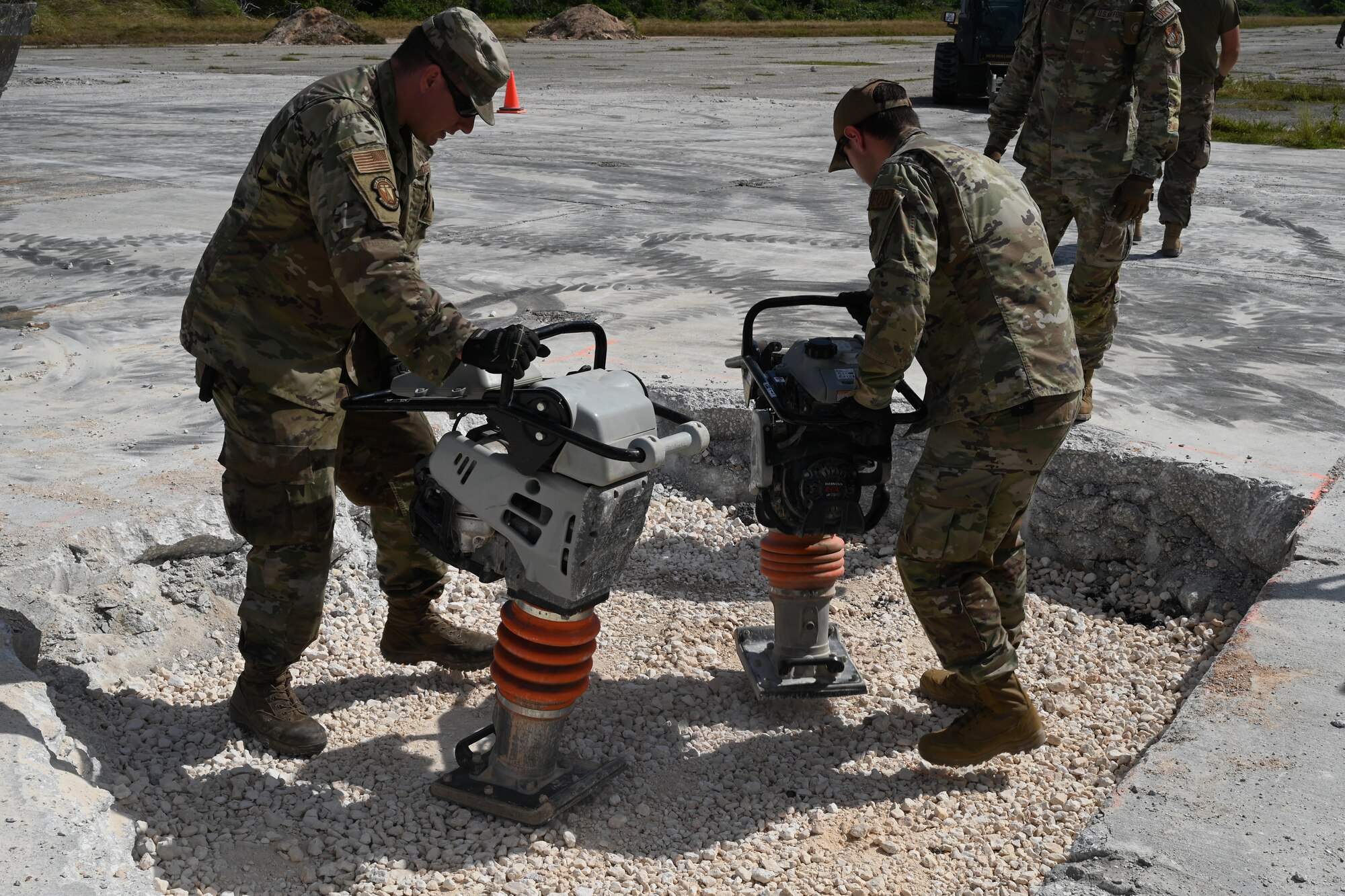 Two Airmen use jumping jack compactors to compress the new material in the crater.
