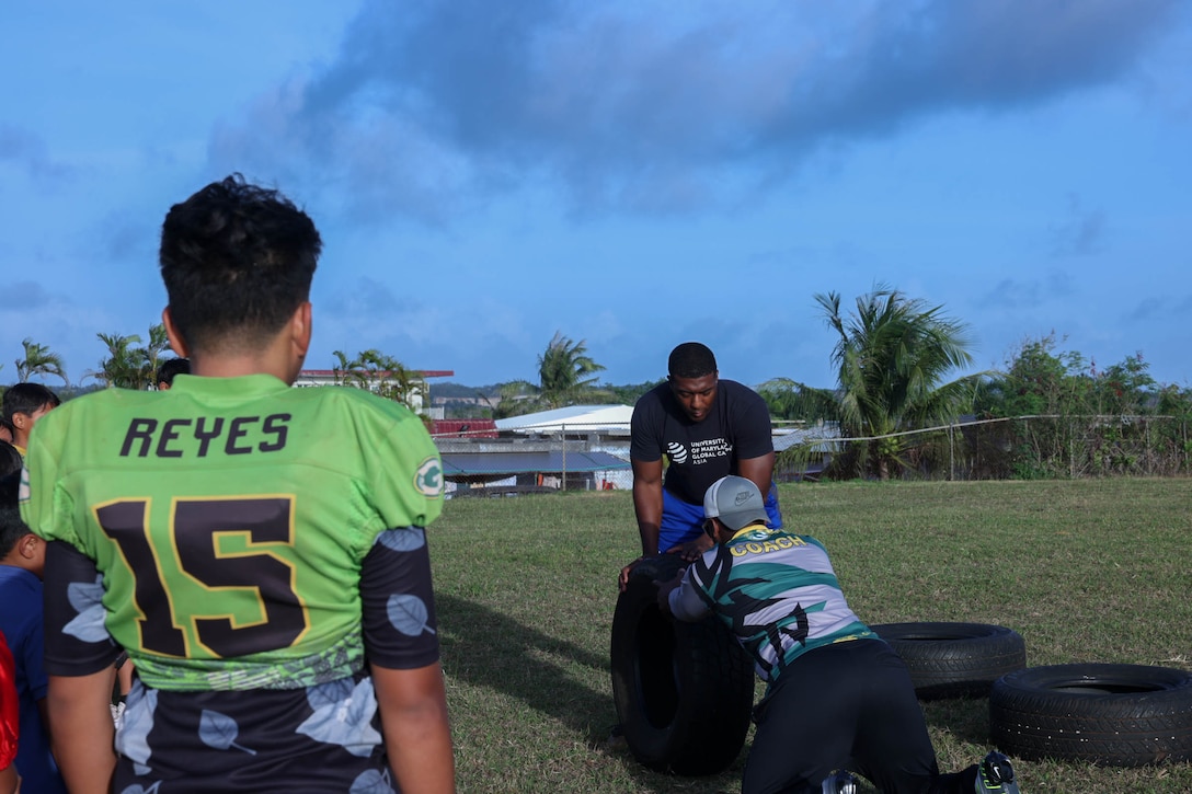 U.S. Marine Corps Sgt. Jacari Williams, a New Orleans native, and a personnel chief stationed on Marine Corps Base Camp Blaz and a volunteer coach, demonstrates how to conduct an explosive forward push with Wes Lane, a volunteer football coach, April 10, 2024. Williams in his free time helps coach the Guam Green Bay Packers, a youth football group, to inspire them to find success in life with what he teaches through football. (U.S. Marine Corps photo by Lance Cpl. Rey Moreno Marilao)