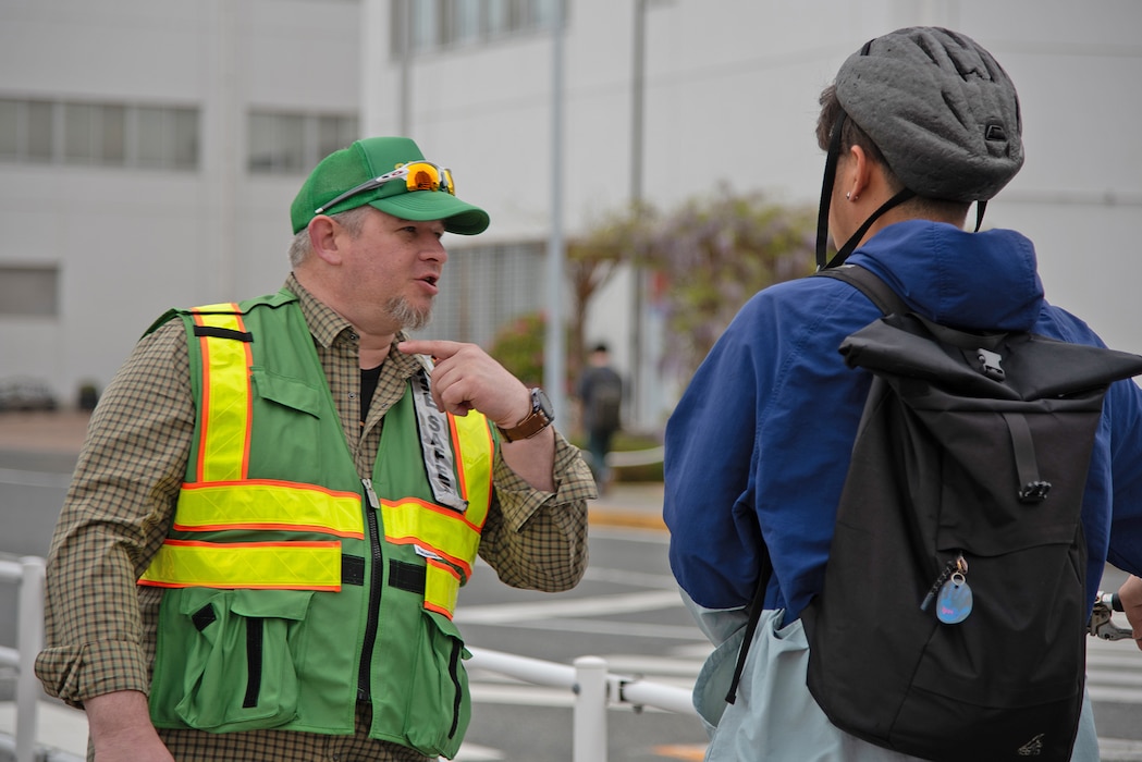 Charles Lapointe, a participating member of the street safety campaign hosted by the safety department of Commander, Fleet Activities Yokosuka (CFAY), speaks to a cyclist explaining bicycle safety rules during CFAY’s street safety campaign.
