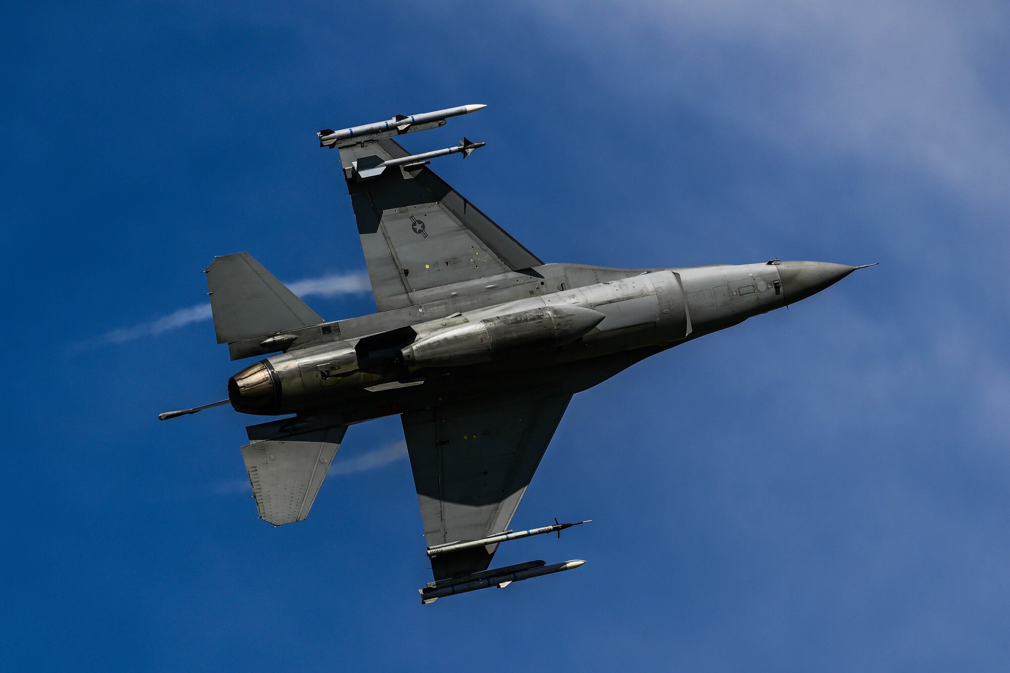 An F-16 flies across the sky.