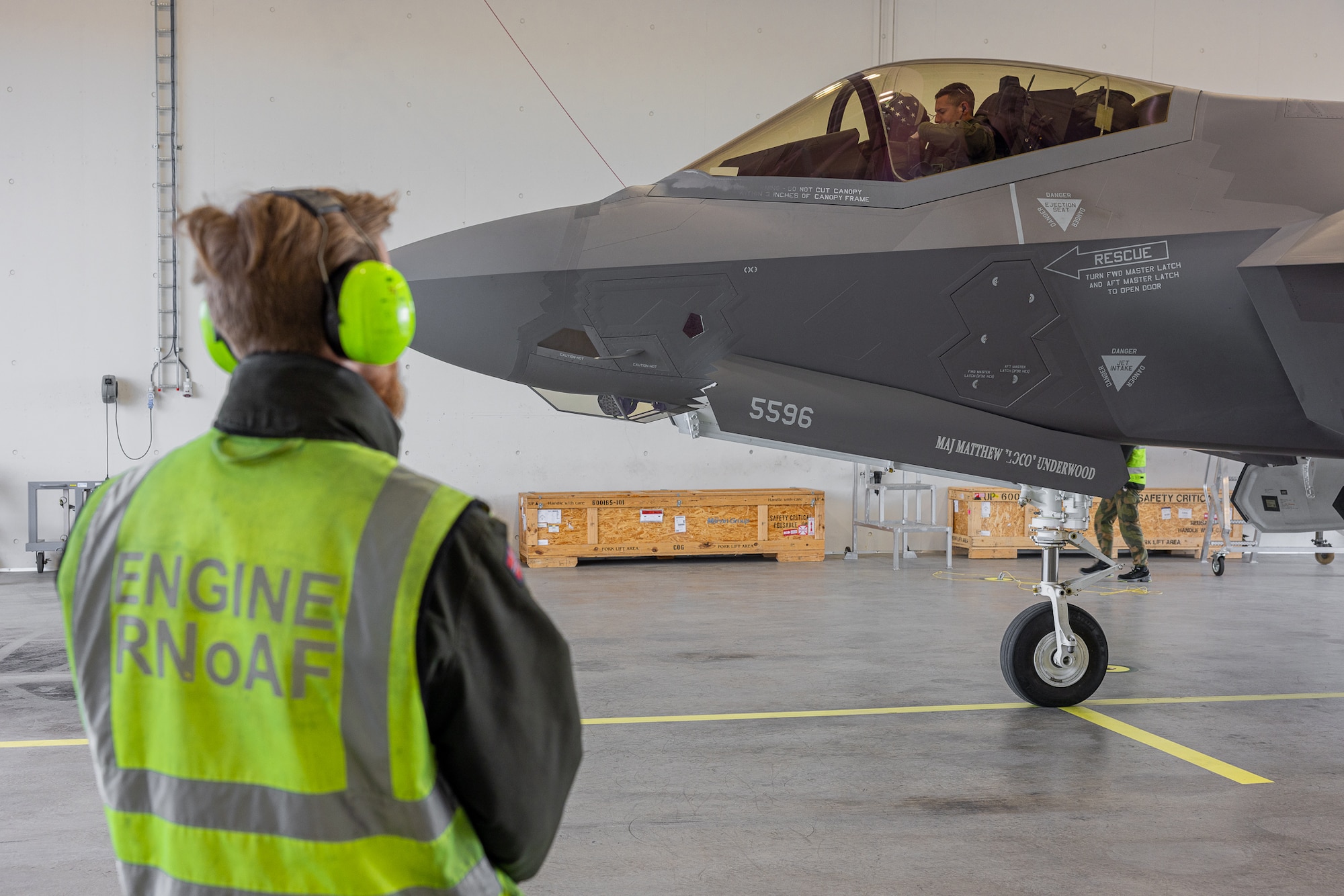 A Royal Norwegian Air Force Airman watches as a U.S. F-35 Lightning II pilot prepares to disembark the aircraft after a flight from RAF Lakenheath in the United Kingdom to Ørland Main Air Station in Norway, April 8, 2024. A team of Norwegian Airmen received the U.S. aircraft and pilot, and prepared the aircraft for its next mission. The mission marked the first time that Airmen from one nation’s military provided servicing to another nation’s F-35 aircraft without supervision. The cross servicing of aircraft between NATO partners highlights the future interoperability with fellow F-35 users across the European Theater.” (RNoAF photo by Ole Andreas Vekve)