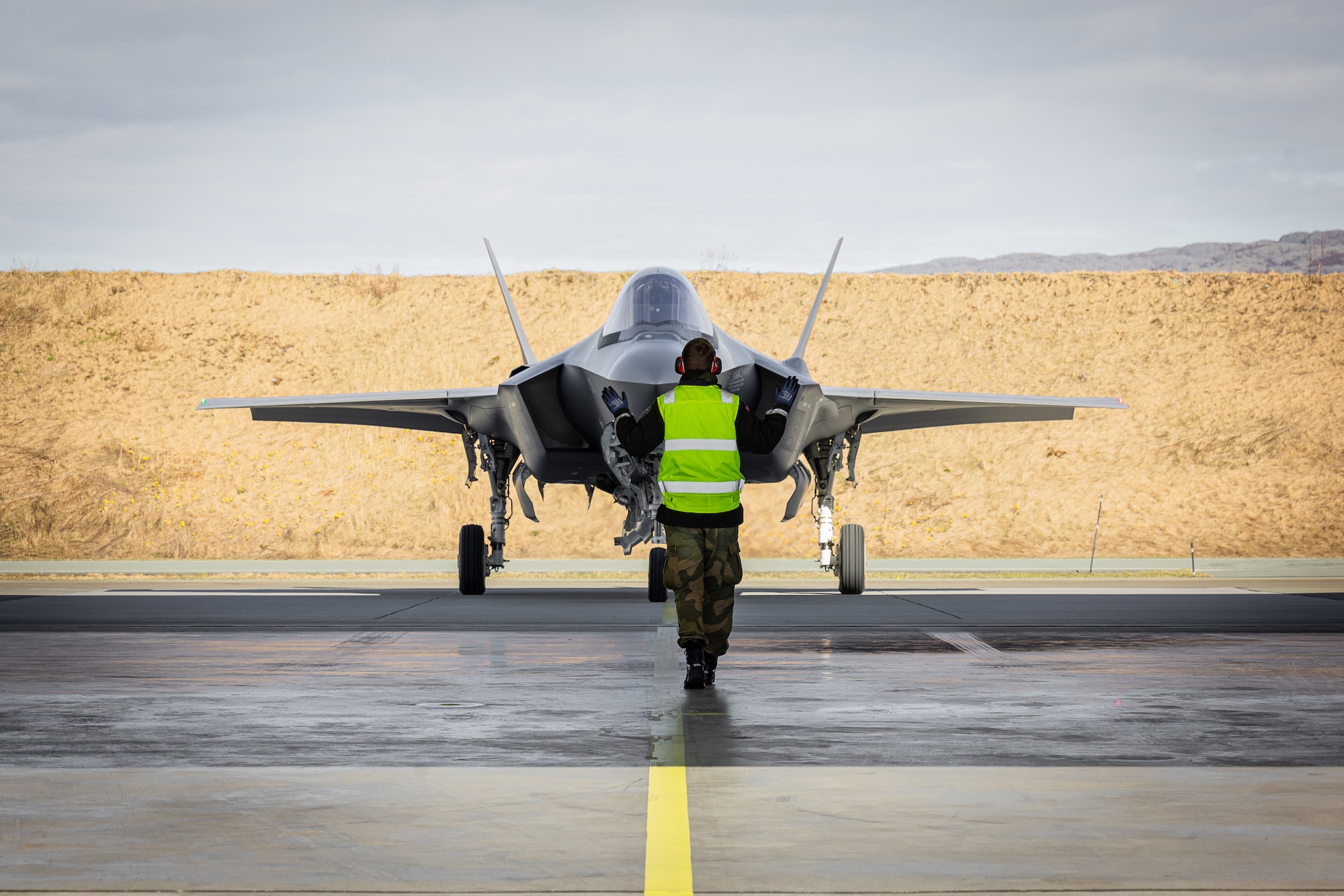 A Royal Norwegian Airman marshals in a U.S. F-35 Lightning II aircraft into a hangar at Ørland Air Station in Norway, April 8, 2024. The mission marked the first time that Airmen from one nation’s military provided servicing to another nation’s F-35 aircraft without supervision. The cross servicing of aircraft between NATO partners highlights the future interoperability with fellow F-35 users across the European Theater. (RNoAF photo by Ole Andreas Vekve)