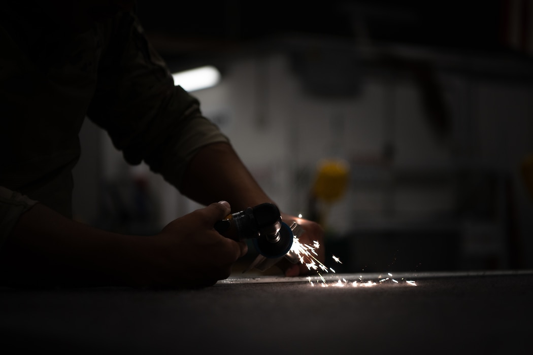 A U.S. Air Force aircraft metals techonology journeyman grinds a piece of titanium at an undisclosed location within the U.S. Central Command area of responsibility, April 16, 2024.