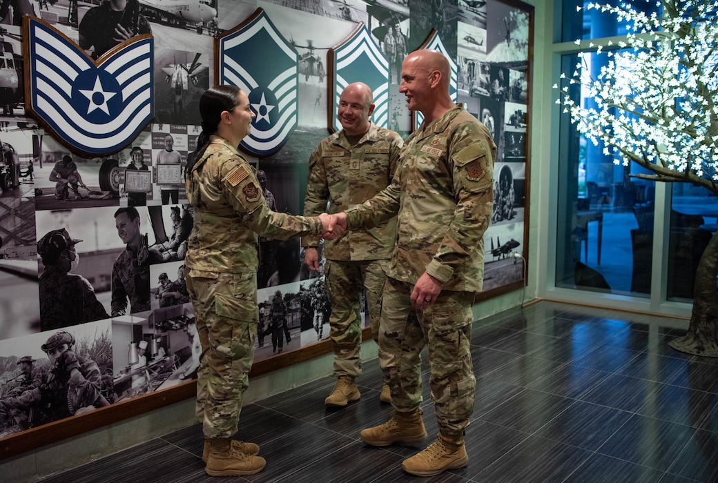 Chief Master Sgt. of the Air Force David Flosi coins U.S. Air Force Senior Airman Lillie Jimenez Guzman, 353rd Special Operations Wing imagery analyst, during his visit to Kadena Air Base, Japan