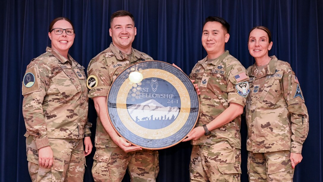 Vosler Academy Fellowship II fellows present a gift to the Vosler Academy leadership during an induction ceremony at Peterson Space Force Base, Colo., April 19, 2024. The Fellowship II curriculum—which remains a five-week course—is enriched with foundational Space Force competencies, ensuring a comprehensive understanding of space-centric roles. (U.S. Air Force photo by Capt. Charles Rivezzo)