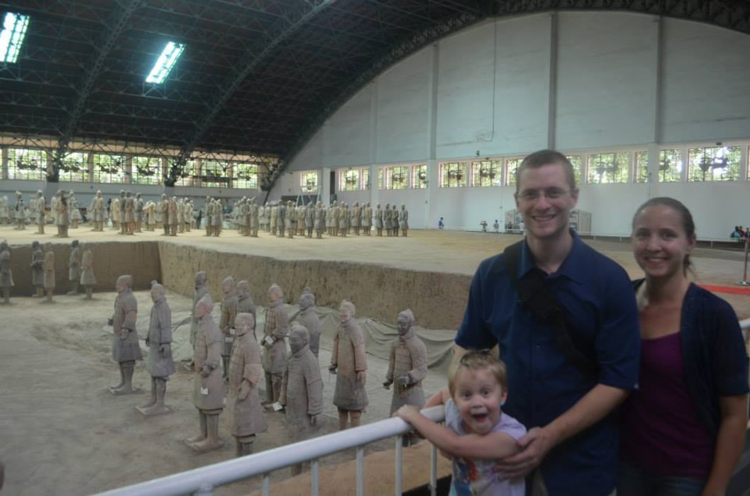 a family portrait in front of terra cotta army sculptures