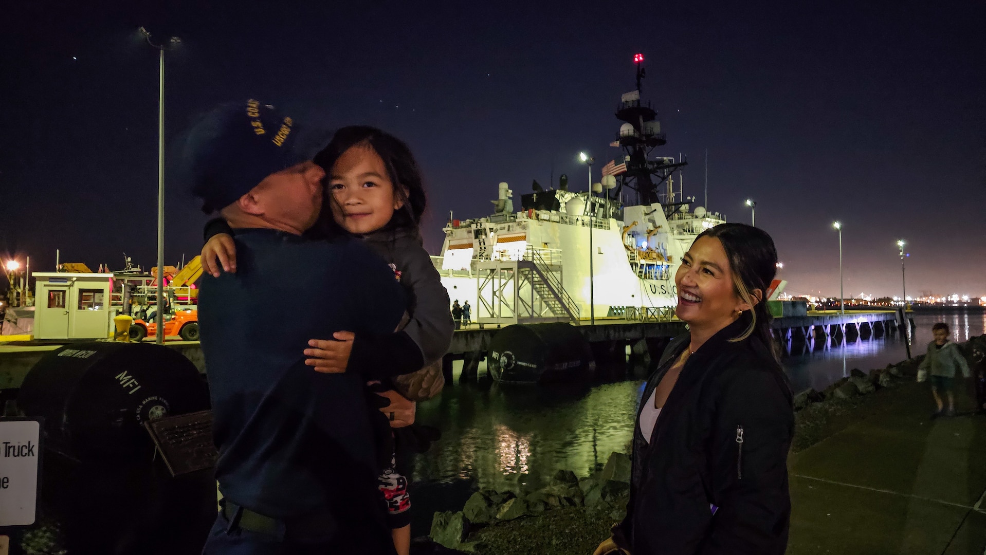 A U.S. Coast Guard Cutter Stratton (WMSL 752) crewmember hugs his child after returning to home port in Alameda, Calif., April 21, 2024. Stratton and crew conducted a 111-day Alaska deployment to the Bering Sea in support of search and rescue capabilities and protecting the United States’ northern-most borders. (U.S. Coast Guard photo by Senior Chief Petty Officer Charly Tautfest)