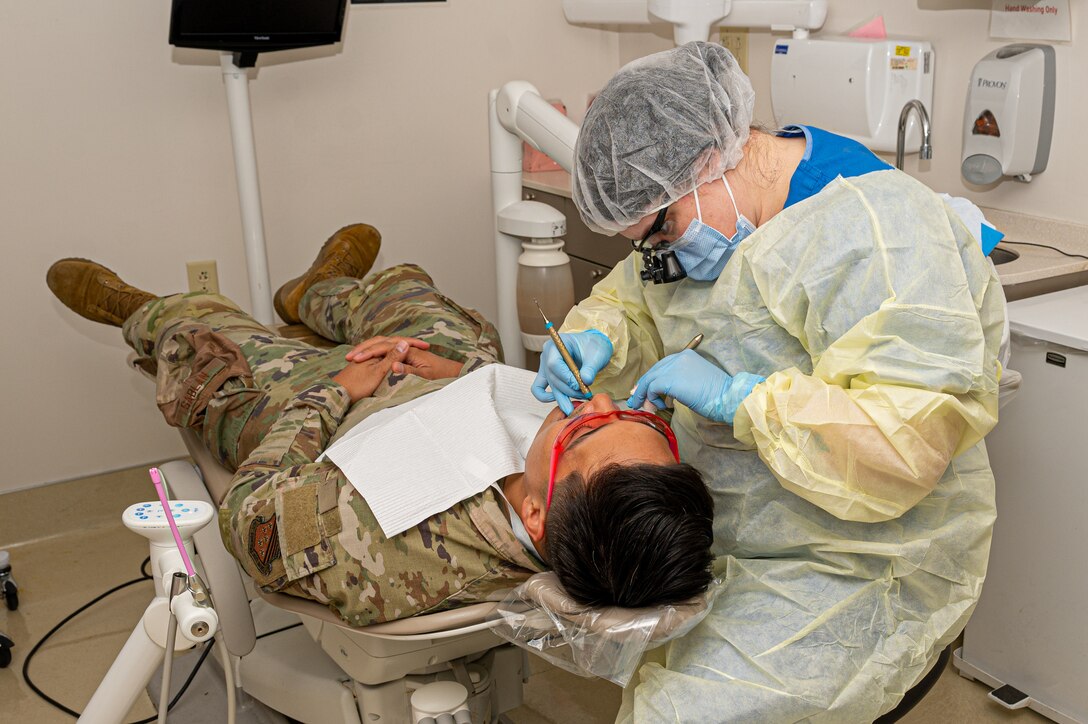 U.S. Air Force Staff Sgt. Emily Crabtree, 633d Dental Squadron oral preventative assistant, cleans the teeth of Senior Airman Caleb, 1st Maintenance Group analyst in the dental clinic at Joint Base Langley-Eustis, Virginia, April 4, 2024. Crabtree used a scaler to remove plaque and tartar from the patient’s gum line, which helps reduce the risk of gum disease.  (U.S. Air Force photo by Airman 1st Class Skylar Ellis)
