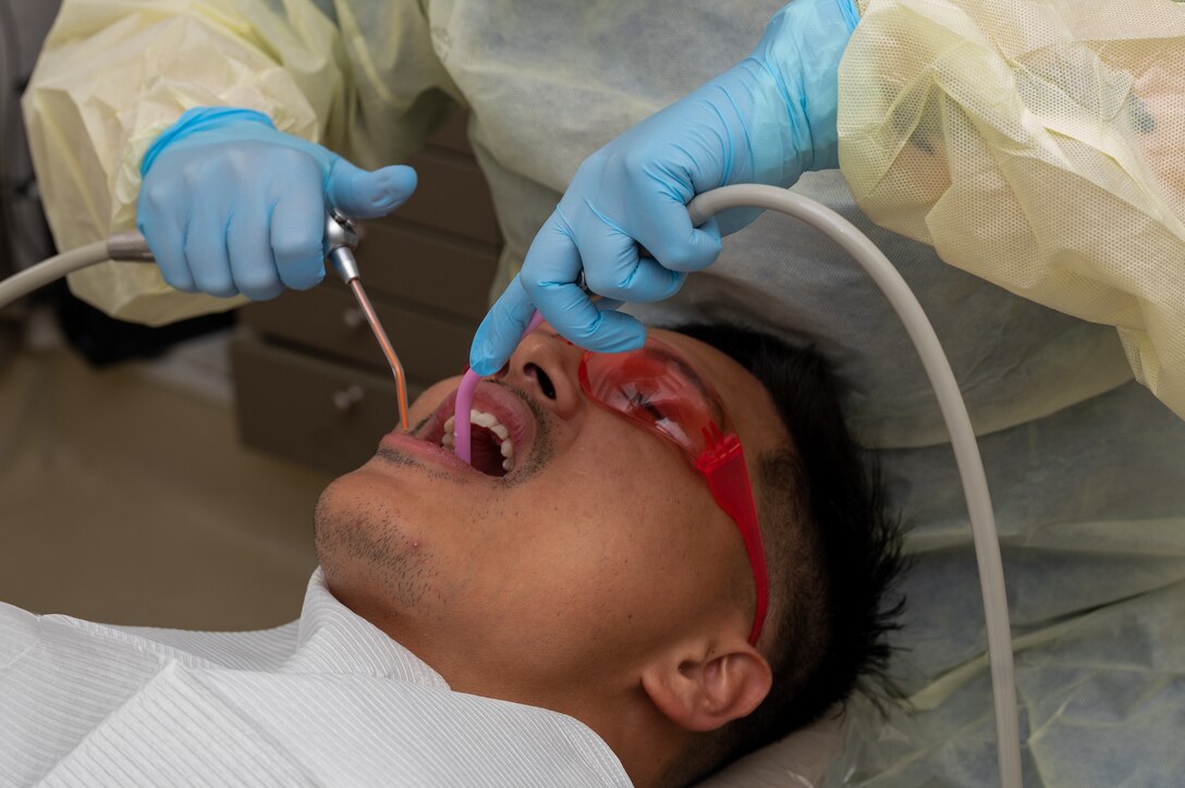 U.S. Air Force Senior Airman Caleb, 1st  Maintenance Group analyst, receives an annual dental check up at the 633d Dental Squadron at Joint Base Langley-Eustis, Virginia, April 4, 2024. The air-water syringe and suction tool allow dental assistants to efficiently irrigate and dry the area being worked on. (U.S. Air Force photo by Airman 1st Class Skylar Ellis)
