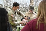 Staff Sgt. Christopher Davenport, a U.S. Army Medical Center of Excellence Soldier, demonstrates to a group of scouts how to splint a broken arm as part of a first aid skill demonstration at the Council-wide Campout that took place in San Antonio on March 2, 2024.